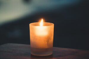 A single lit candle in a dark room, symbolizing reflection and remembrance